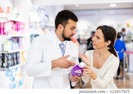 Pharmacist advises customer in pharmacy, offers medicine for body care Pharmacist advises customer in pharmacy, offers medicine for body care 122617925