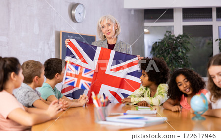 Female teacher showing british flag to kids in geography class Female teacher showing british flag to kids in geography class 122617946