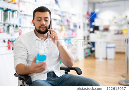 Man in wheelchair using phone at drugstore 122618037