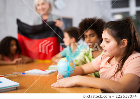Female teacher showing german to kids in geography class Female teacher showing german to kids in geography class 122618074