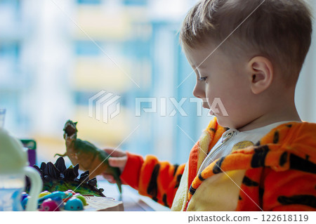 A little one-and-a-half-year-old child is playing with toys by the window, 122618119