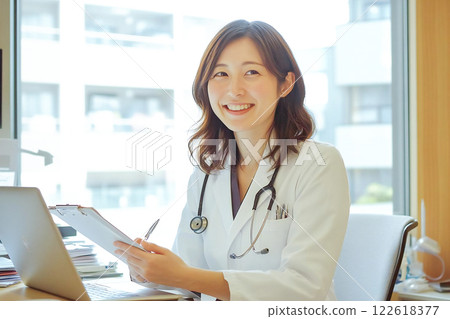 A smiling female doctor checking a patient's chart in the examination room A smiling female doctor checking a patient's chart in the examination room 122618377