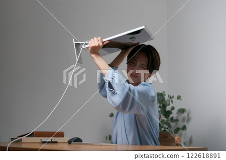 A woman destroys her computer due to stress A woman destroys her computer due to stress 122618891
