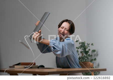 A woman destroys her computer due to stress A woman destroys her computer due to stress 122618892