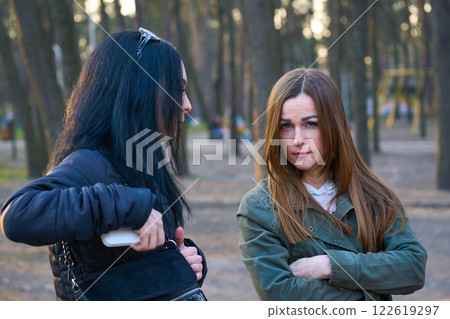 Two young women girlfriends have serious conversation discussion in city park 122619297