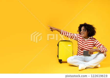An African-American woman with a suitcase and a passport in her hands An African-American woman with a suitcase and a passport in her hands 122619619