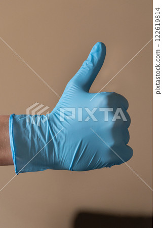 A person who is wearing a bright blue glove is making a wellrecognized peace A person who is wearing a bright blue glove is making a wellrecognized peace 122619814