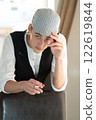 A young man in a cap, a vest, a white shirt, smokes by the window and talks. Bad habits among young people. Young manager. 122619844