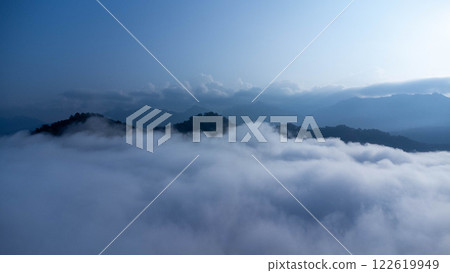 The mountain range with visible silhouettes seen through the colorful fog in the morning. The mountain range with visible silhouettes seen through the colorful fog in the morning. 122619949
