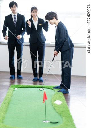 一位女總裁在室內練習推桿，一位年輕員工在奉承她 122620078