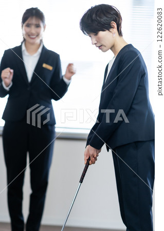 一位女總裁在室內練習推桿,一位年輕員工在奉承她 一位女總裁在室內練習推桿,一位年輕員工在奉承她 122620083