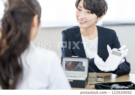 A specialist buyer explaining the estimated price using a calculator A specialist buyer explaining the estimated price using a calculator 122620092