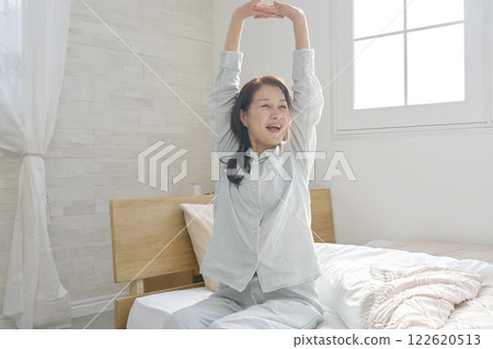 Middle-aged woman stretching and waking up Middle-aged woman stretching and waking up 122620513