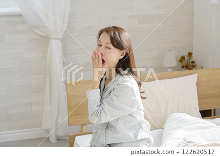Middle-aged woman in pajamas yawning 122620517