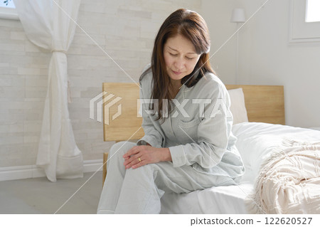 Middle-aged woman in pajamas with painful knee Middle-aged woman in pajamas with painful knee 122620527