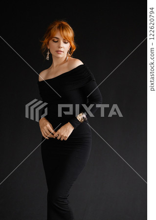 Elegant woman with red hair in black off-the-shoulder dress on dark background Elegant woman with red hair in black off-the-shoulder dress on dark background 122620794