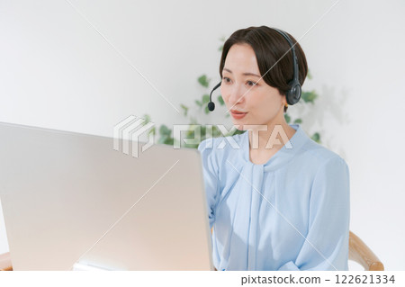 Middle-aged woman having an online meeting while teleworking Middle-aged woman having an online meeting while teleworking 122621334