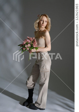 Model poses elegantly with flowers in a stylish indoor setting Model poses elegantly with flowers in a stylish indoor setting 122621903