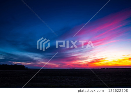A plowed field and a picturesque colorful sunset sky 122622308