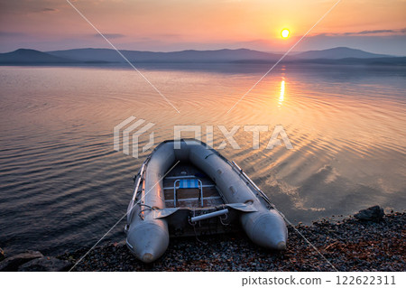 Rubber boat on the shore of the picturesque coast against the backdrop of sunrise Rubber boat on the shore of the picturesque coast against the backdrop of sunrise 122622311
