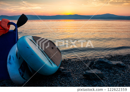 Two sup boards on the shore of a scenic lake against the backdrop of sunset 122622359