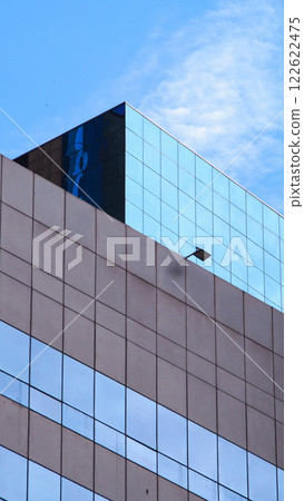 Modern Architectural Symmetry - Minimalist geometric facade with reflective blue glass, ideal for design portfolios, urban planning presentations, or architectural branding Modern Architectural Symmetry - Minimalist geometric facade with reflective blue glass, ideal for design portfolios, urban planning presentations, or architectural branding 122622475