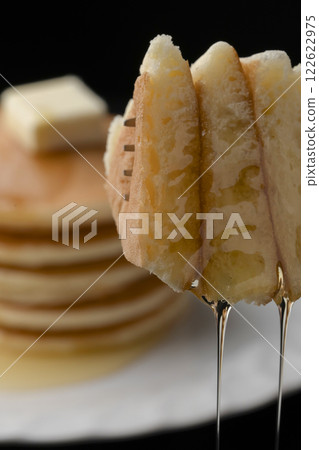 Lifting a hotcake covered in honey with a fork 122622975