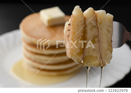 Lifting a hotcake covered in honey with a fork 122622976
