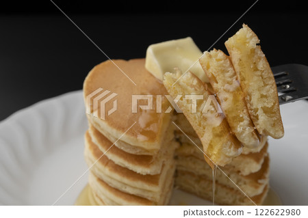 Lifting a hotcake covered in honey with a fork 122622980