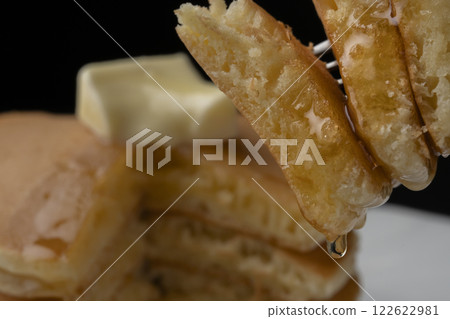 Lifting a hotcake covered in honey with a fork 122622981
