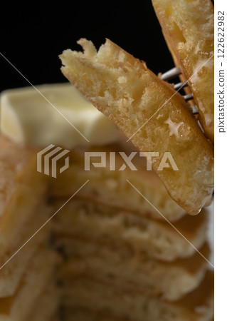 用叉子叉起塗滿蜂蜜的熱餅 用叉子叉起塗滿蜂蜜的熱餅 122622982