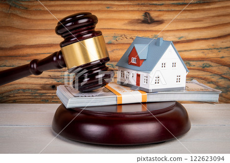 Divorce dispute and agreement concept. Judge's gavel, money and miniature house on a wooden texture Divorce dispute and agreement concept. Judge's gavel, money and miniature house on a wooden texture 122623094