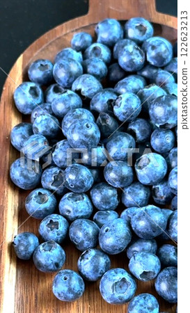 Blueberries grouped on brown wood emphasize rustic appeal and connection to eco lifestyle. Each berry represents symbol of summer harvest, showcasing eco-friendly values, highlighting natural symbol. 122623213