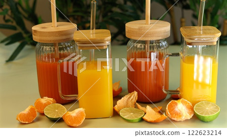 Glass jars with fresh juices placed alongside orange slices, raspberries, and lime peels highlight zero-waste nutrition with eco-conscious containers. Natural balance focus. Glass jars with fresh juices placed alongside orange slices, raspberries, and lime peels highlight zero-waste nutrition with eco-conscious containers. Natural balance focus. 122623214