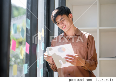 Young businessman analyzing financial data and market trends for investment decisions 122625013