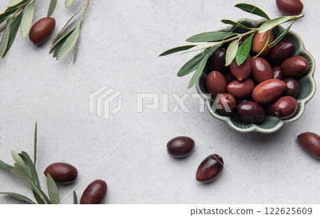 Kalamata olives with olive branch in green bowl on marble background Kalamata olives with olive branch in green bowl on marble background 122625609