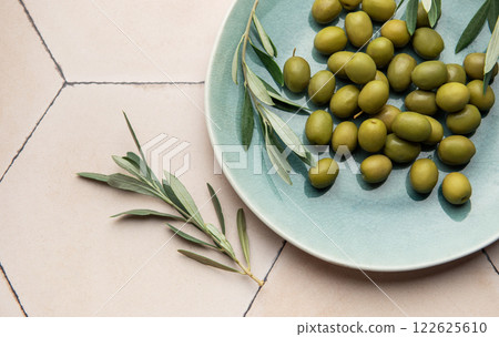 Fresh green olives with olive branch on rustic ceramic plate Fresh green olives with olive branch on rustic ceramic plate 122625610