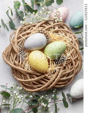 Easter eggs lying in nest surrounded by flowers and eucalyptus leaves Easter eggs lying in nest surrounded by flowers and eucalyptus leaves 122625613
