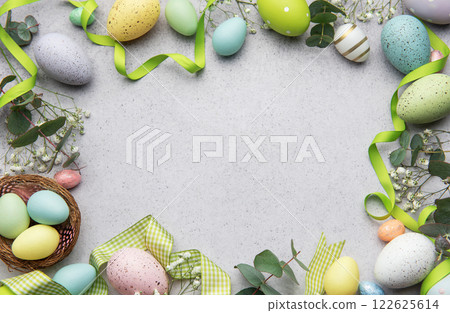 Easter eggs frame decorating a gray surface with ribbons and flowers Easter eggs frame decorating a gray surface with ribbons and flowers 122625614