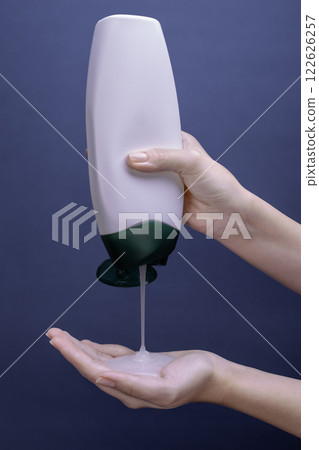 Shower gel in white bottle poured into woman palm 122626257