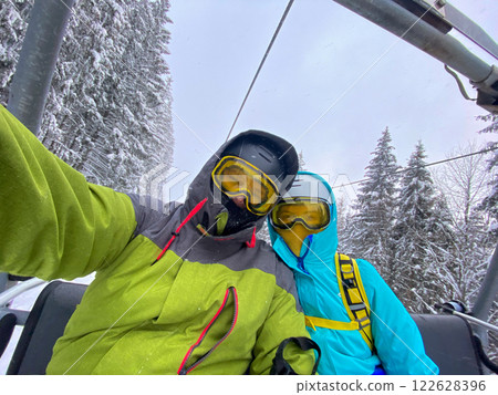Skiers on a Lift in Snowy Forest Skiers on a Lift in Snowy Forest 122628396
