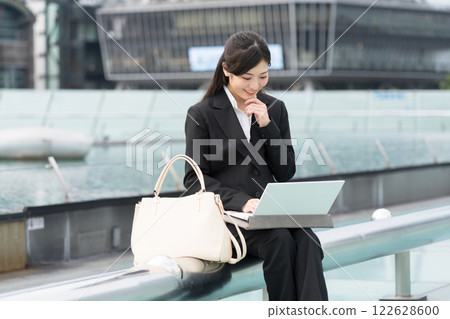 名古屋榮市 OASIS21 水上太空船,一位微笑的女商人正在戶外看著筆記型電腦 名古屋榮市 OASIS21 水上太空船,一位微笑的女商人正在戶外看著筆記型電腦 122628600