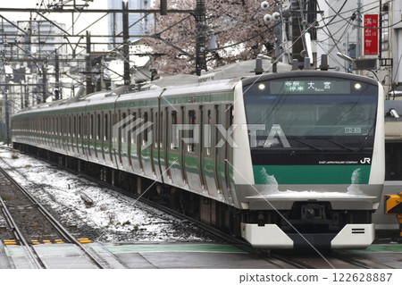 Snowfall obscuring the cherry blossoms and the Saikyo Line E233 series train 122628887