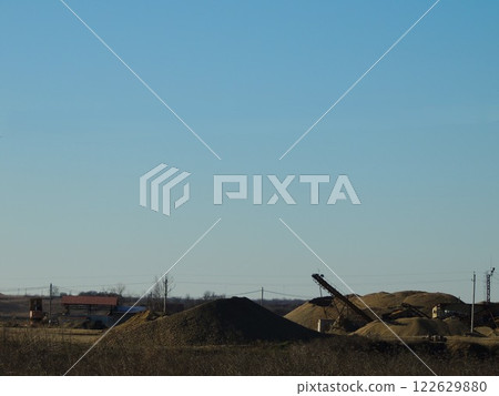 extraction of natural stone by mechanical processing, quarry and open-pit mining in open terrain, brown rock piled up in heaps at the site of development and sale of building gravel material extraction of natural stone by mechanical processing, quarry and open-pit mining in open terrain, brown rock piled up in heaps at the site of development and sale of building gravel material 122629880