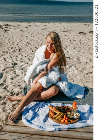 Woman Enjoying a Beachside Picnic on a Sunny Day Woman Enjoying a Beachside Picnic on a Sunny Day 122630321
