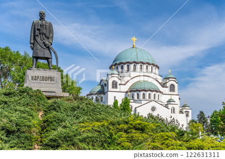 The Karadorde Monument stands proudly by the Saint Sava Cathedral in Belgrade, Serbia, showcasing its historical significance against a clear blue sky and lush greenery. The Karadorde Monument stands proudly by the Saint Sava Cathedral in Belgrade, Serbia, showcasing its historical significance against a clear blue sky and lush greenery. 122631311