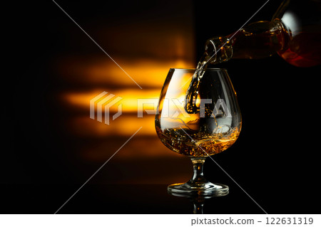 Pouring brandy from a bottle into a snifter. 122631319