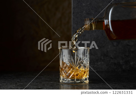Pouring whiskey from a bottle into a glass. 122631331