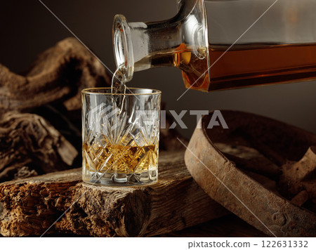 Whiskey is poured from a decanter into a glass. Whiskey is poured from a decanter into a glass. 122631332