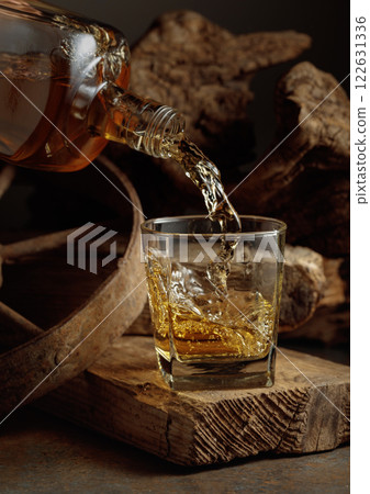 Whiskey is poured from a bottle into a glass. Whiskey is poured from a bottle into a glass. 122631336